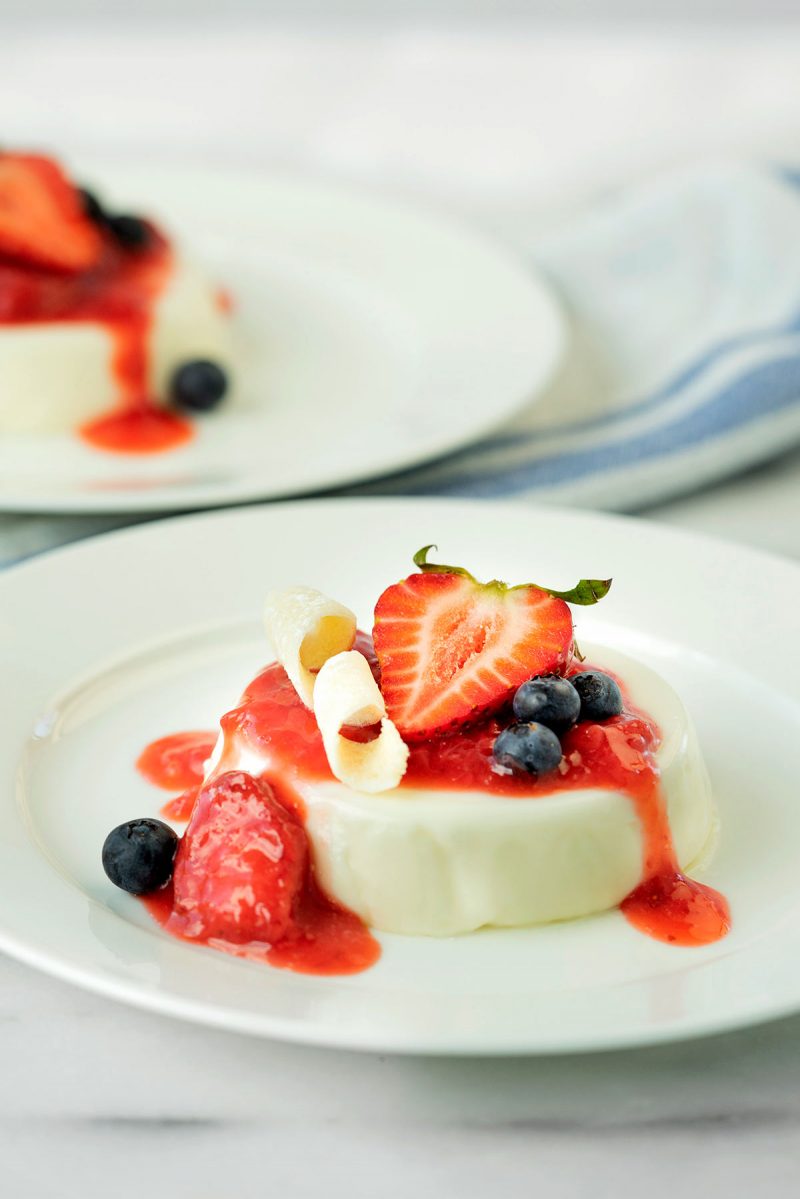 plate of panna cotta with fresh berries and a tuile