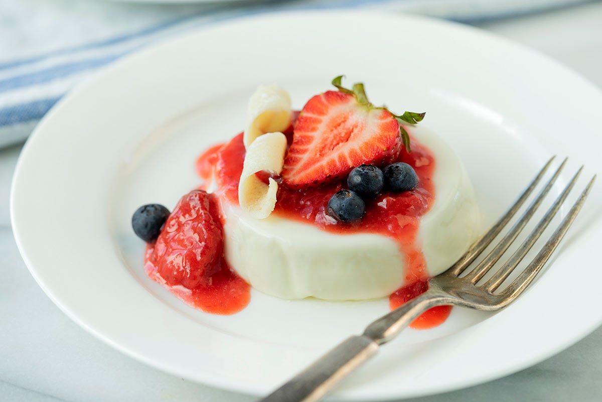 plate of panna cotta with strawberries, white chocolate and blueberries