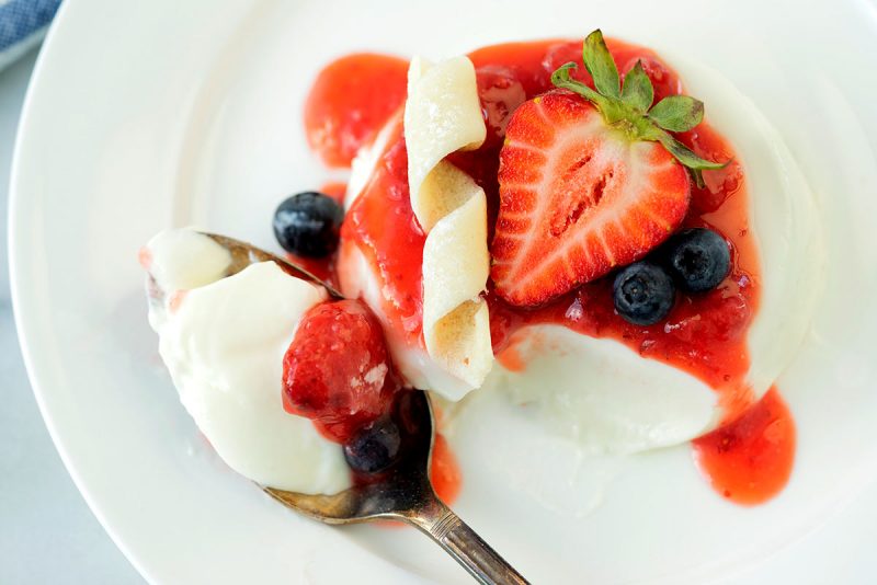 close up on taking a bite of panna cotta with fresh berries