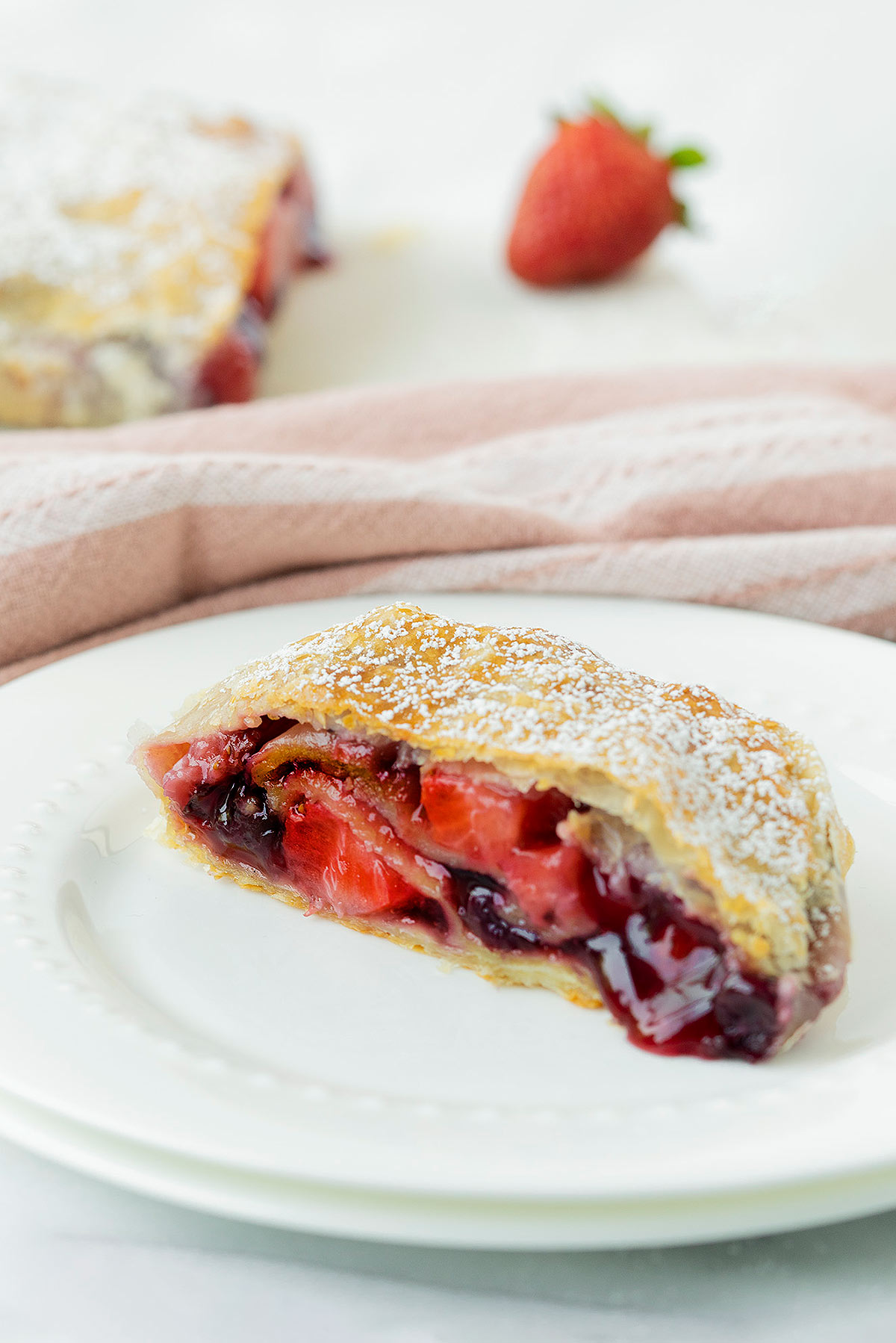 slcie of apple berry strudel on a white plate