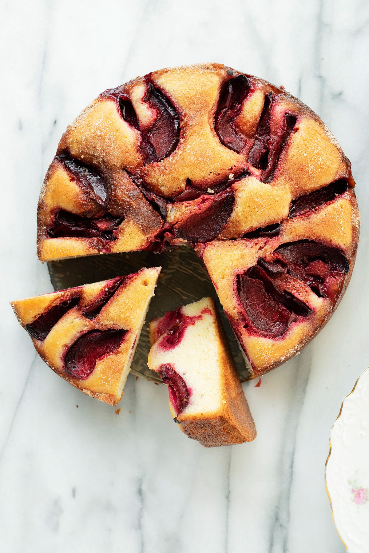 plum cake with slices cut out on a marble background