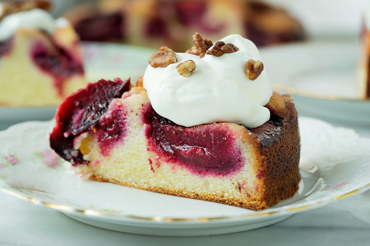 slice of a plum cake with whipped cream on top