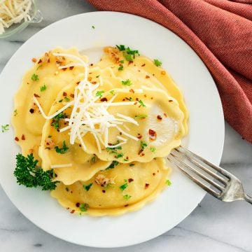 white plate with ravioli, garlic and red pepper flakes