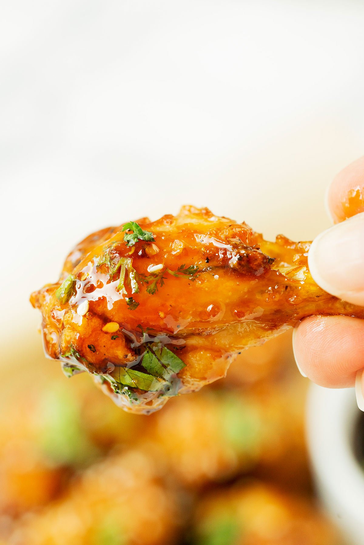 hand holding an air fryer chicken wing with sesame soy sauce