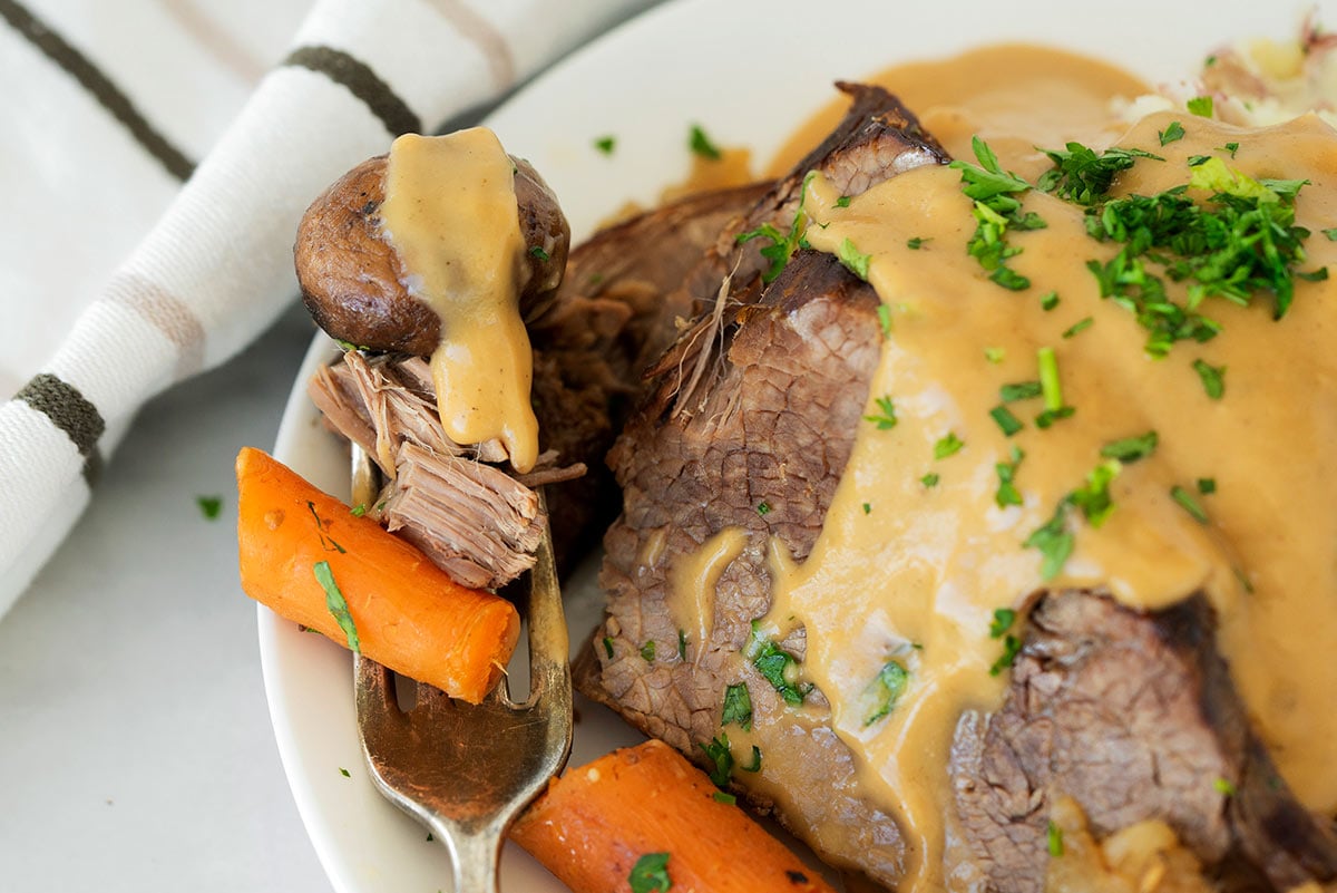 slices of round roast beef with gravy and carrots