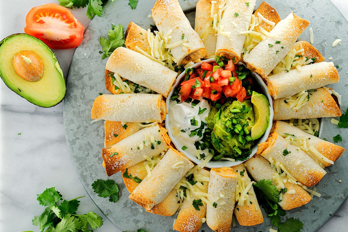 plate of chicken and cheese taquitos with guacamole and salsa