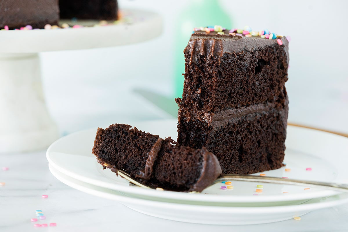 slice of black magic cake on a plate with frosting