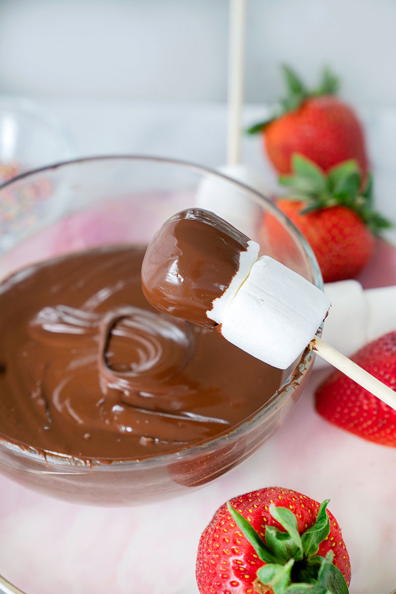 Dipping marshmallows in chocolate fondue