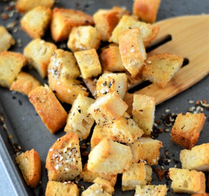 bread cubes on a baking sheet tossed in everything bagel seasoning