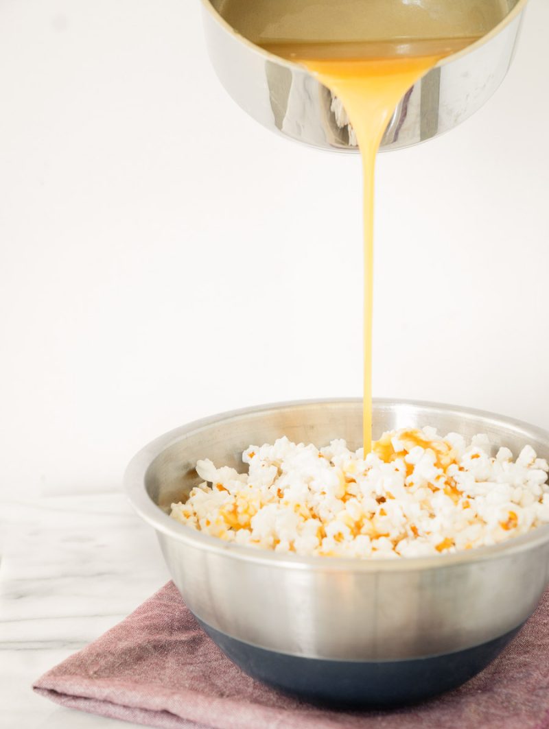 caramel being drizzled over a bowl of popcorn