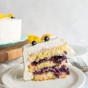 a slice of layered blueberry lemon cake with white icing