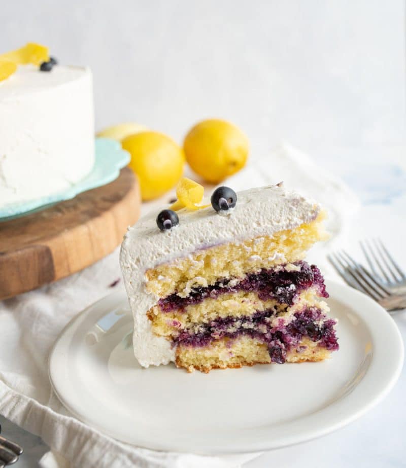 a slice of layered blueberry lemon cake with white icing