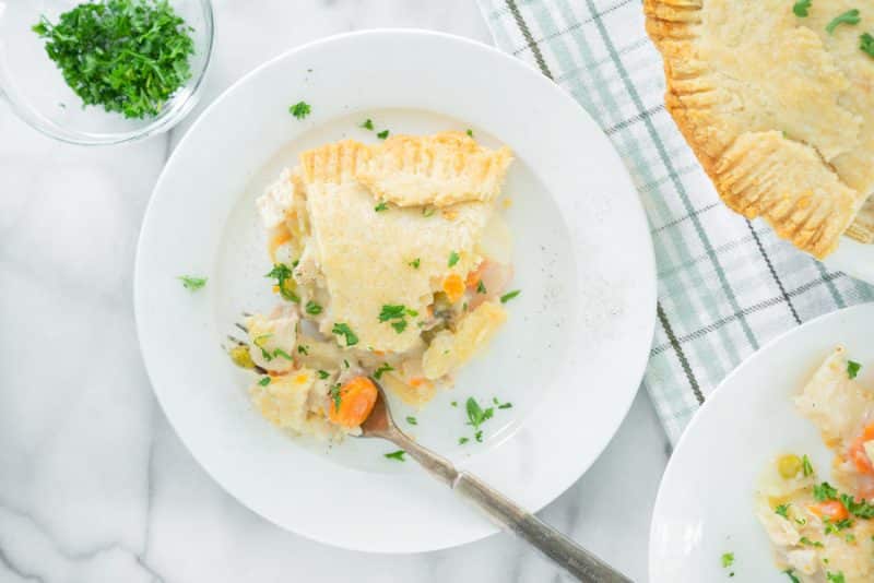 one slice of chicken pot pie on a white plate with a fork
