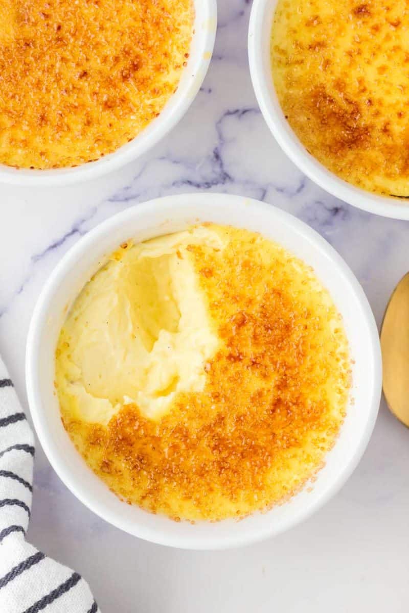 cooked creme brulee in white ramekin with a scoop taken out