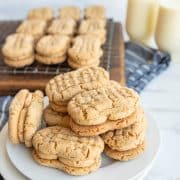 white plate of nutter butter cookies with milk in the background