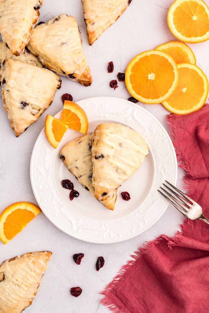 plate of cranberry orange scones with slices of oranges next to it