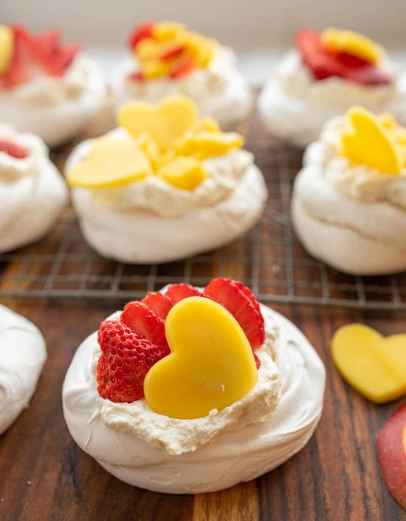 Strawberries and a yellow mango heart top fluffy bakes meringue on these pavlova bits on a cooling rack