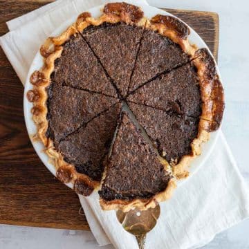 whole chocolate chess pie with a serving utensil taking out a piece