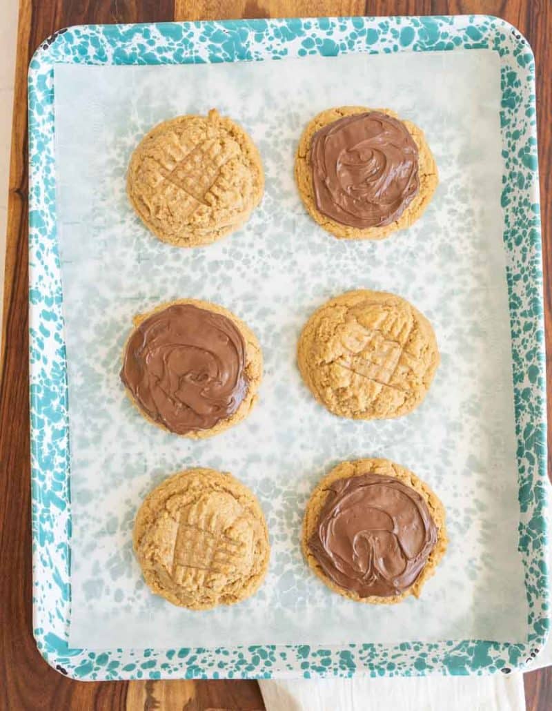 peanut butter cookies with nutella on half, on the cooking sheet