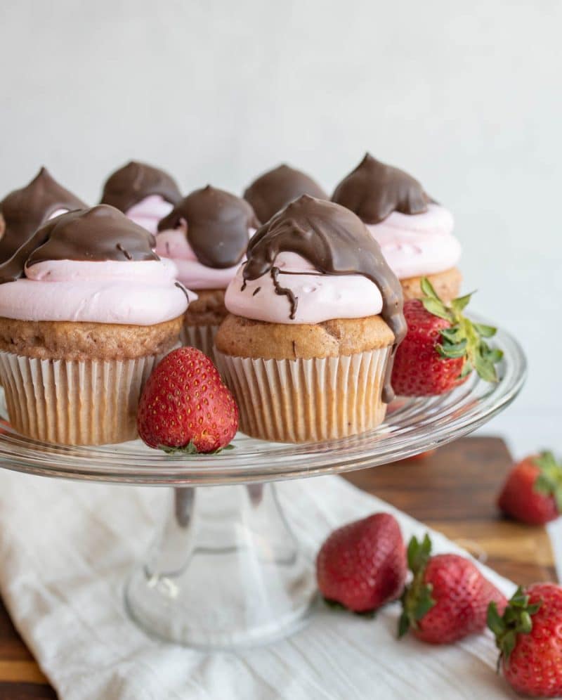 Chocolate covered strawberry cupcakes displayed on a glass platter.