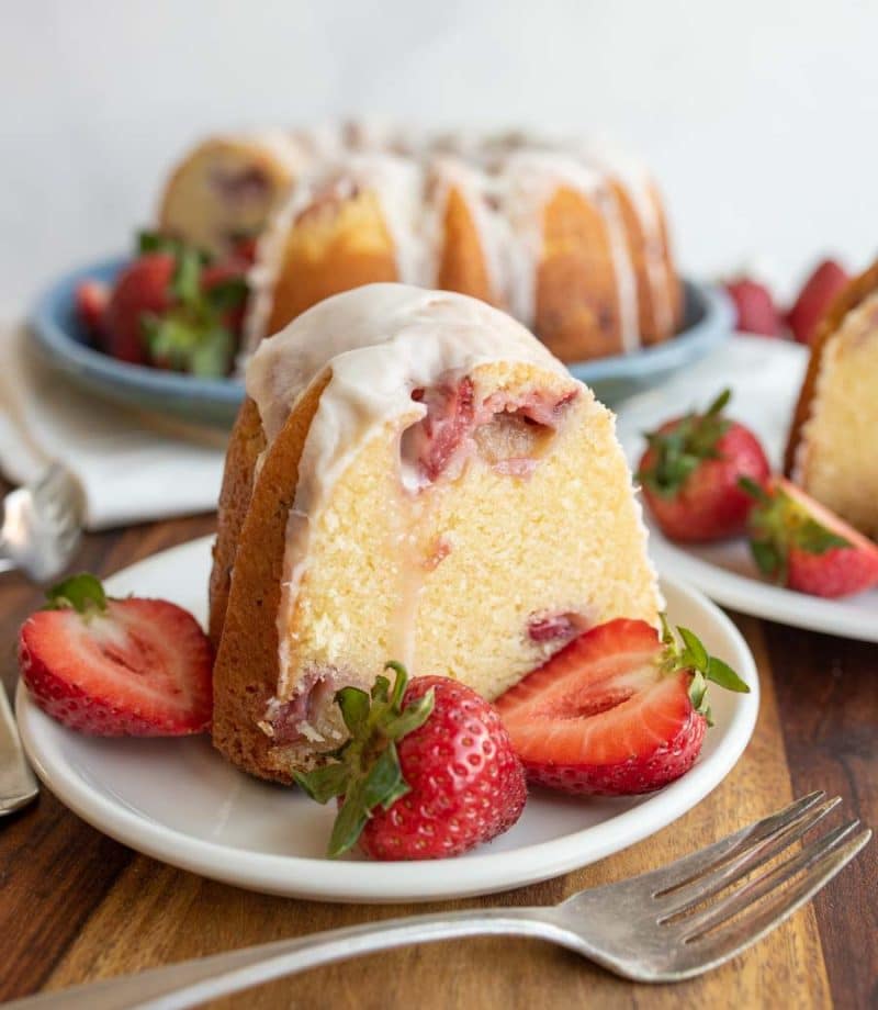Slice of strawberry pound cake on a plate surrounded with strawberries.