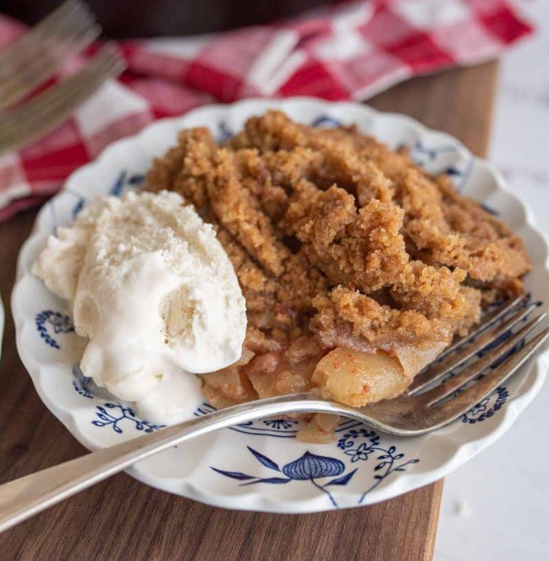 cast iron apple crumble served onto plates with ice cream close up