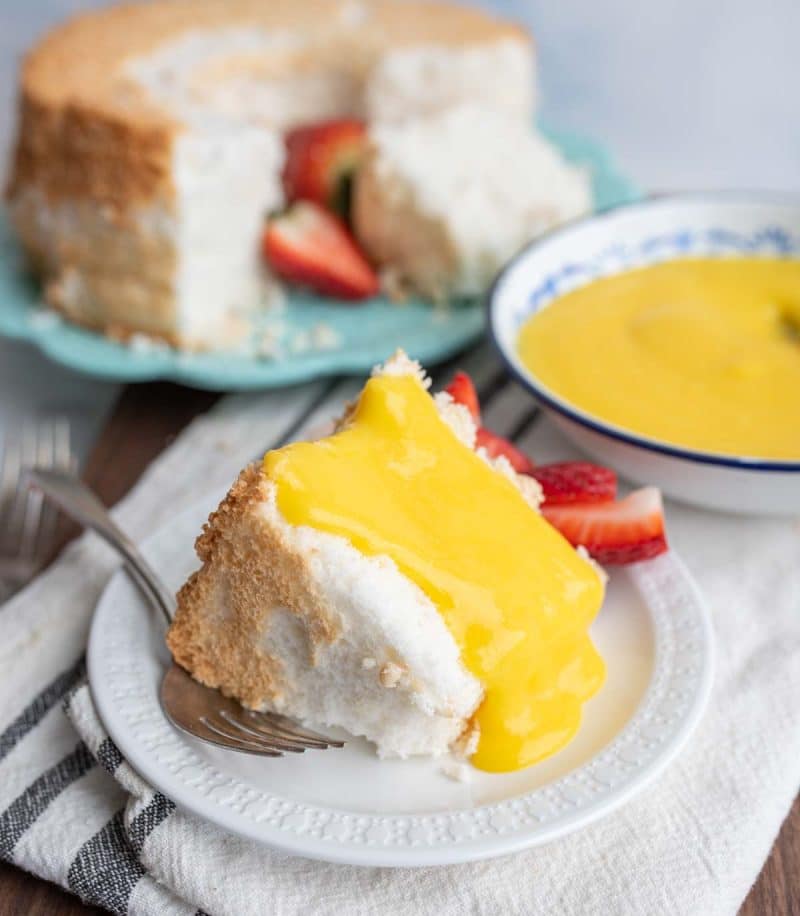 bright yellow lemon curd poured across a wedge of angel food cake