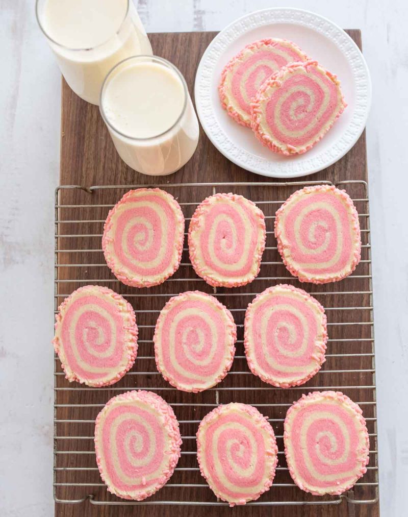 pink and white pinwheel cookies with a swirl design and pink sprinkles on the edges