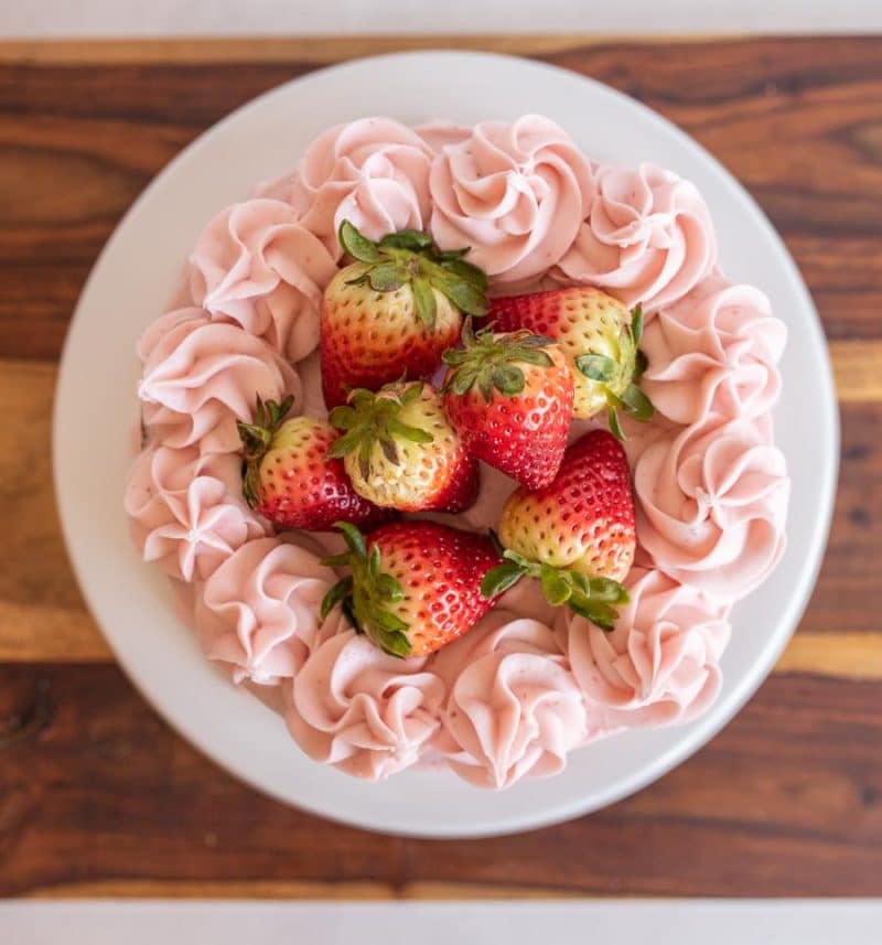 Beautiful display of strawberry buttercream and fresh strawberries on top of a cake.