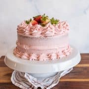 Beautiful, pink frosted cake garnished with strawberries