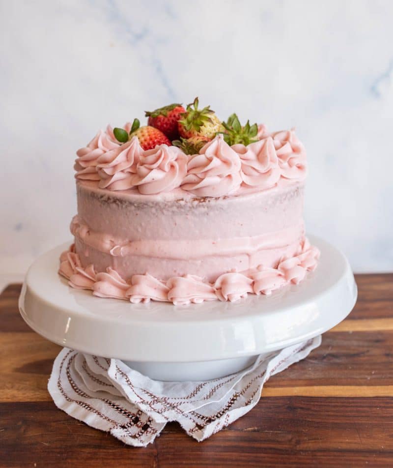 Beautiful, pink frosted cake garnished with strawberries.
