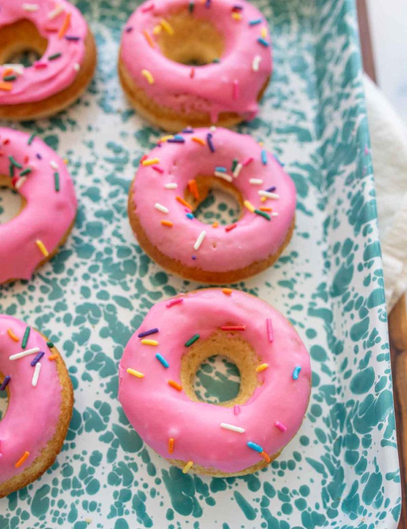 round baked donuts with pink icing and rainbow sprinkles