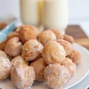 close up plate of a stack of round iced and sugar donut holes