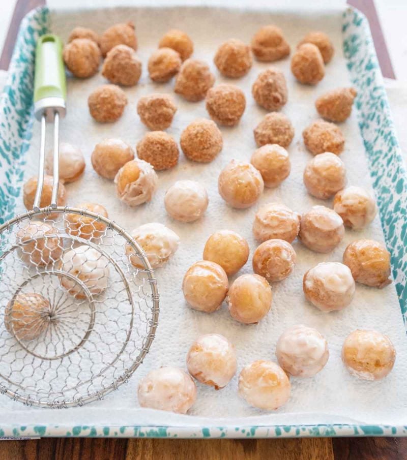 round iced and sugar donut holes on a baking sheet