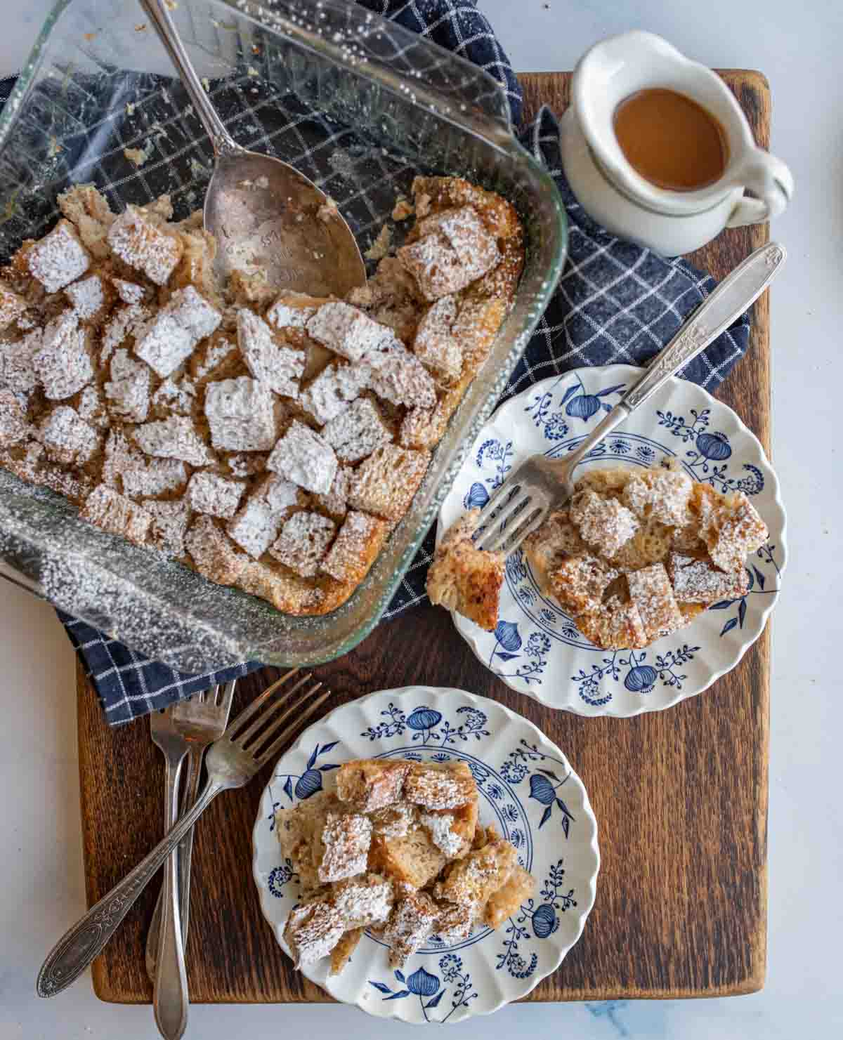bread pudding in a whole casserole dish and then portioned on two white and blue china plates