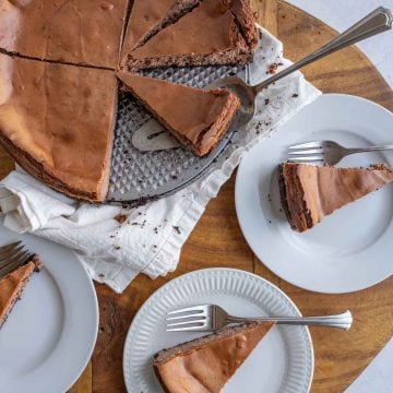 top aesthetic view of a chocolate cheesecake and several servings on white plates