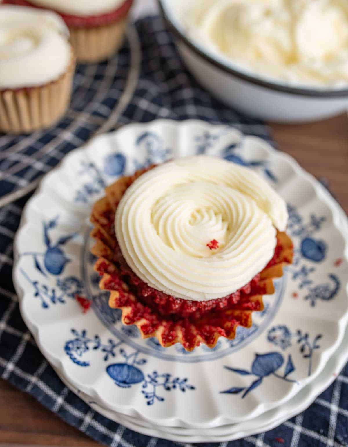 red velvet cupcake with cream cheese frosting on white and blue plate