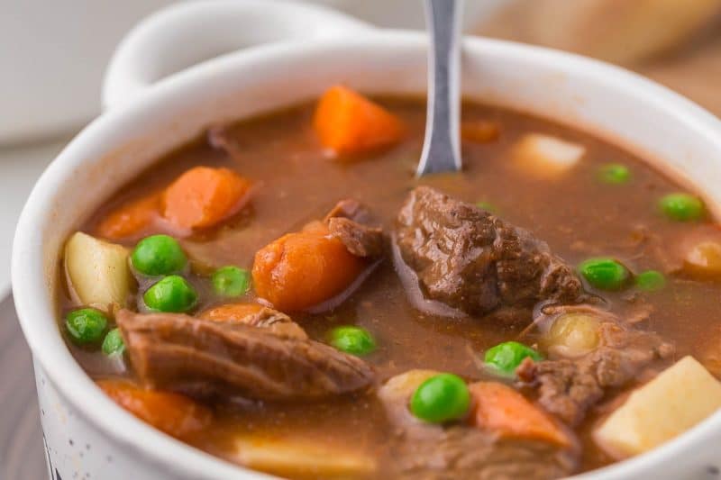 close up of one serving of round steak beef stew in a round white soup bowl