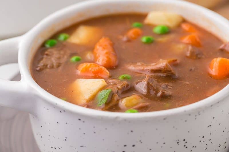 close up of one serving of round steak beef stew in a round white soup bowl