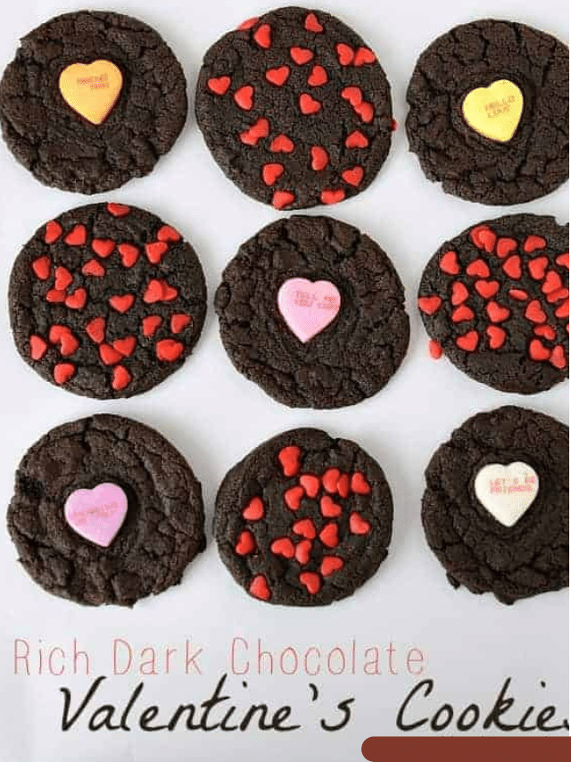 Nine rich dark chocolate decorated Valentine Day cookies are arranged in a grid. Some are topped with tiny red heart sprinkles, others with pastel candy hearts with messages, on a white background that reads “Rich Dark Chocolate Valentine’s Cookie.”.