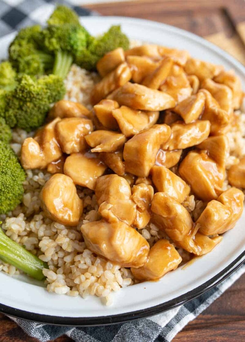 A plate of brown rice topped with teriyaki chicken pieces and served with steamed broccoli florets—a delicious take on the classic teriyaki chicken recipe.
